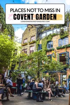 people sitting on benches in front of a building with plants growing up the side of it