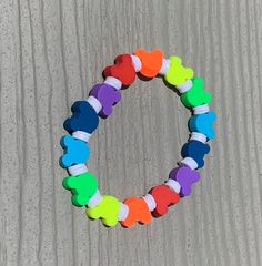 a multicolored bracelet with hearts on it sitting on the ground next to a piece of wood