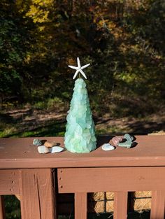 a small green christmas tree sitting on top of a wooden table next to rocks and starfish