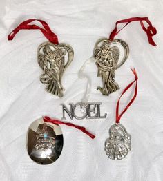 three ornaments are laying on a white sheet with red ribbon around them and the words noel written in silver