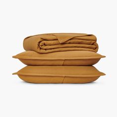 three pillows stacked on top of each other in front of a white background, with one folded