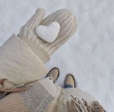 someone wearing mittens and gloves with a white heart on their thumb, in the snow