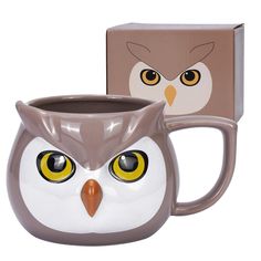 an owl shaped coffee mug with yellow eyes sits next to a cardboard box that has the image of an owl's face on it