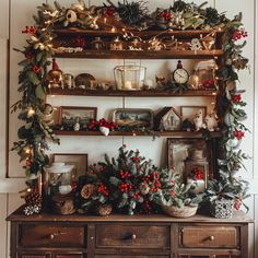 an old dresser is decorated with christmas decorations and greenery, including holly garlands