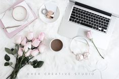 a laptop computer sitting on top of a white fur covered floor next to pink roses