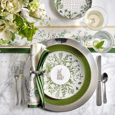 the table is set with green and white plates, silverware, and napkins