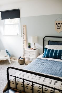 a bed room with a neatly made bed and a tall ruler hanging on the wall