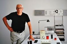 an older man standing next to a table with electronics on it