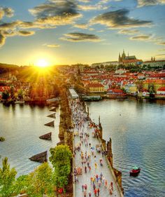 the sun is setting over a river with many people walking on it