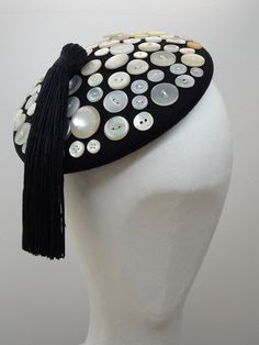 A neat, black felt mini beret hat with lovely array of vintage buttons - finished with a luscious tassel. This unique hat is fun and easy to wear but sure to get you noticed - perfect for steampunk costume events, anything London or cockney themed, burlesque, music hall or dressing as a pearly queen! The underside is finished with traditional petersham ribbon and lined with satin. The hat base is approx 17.5cm in diameter and sits just under 4cm high excluding the tassel. The tassel is 14cm long Vintage Handmade Black Mini Hats, Handmade Vintage Black Mini Hats, Unique Fascinators, Corporate Gowns, Unusual Hats, Fascinator Hats Diy, Couture Hats, Hat Base, Diy Buttons