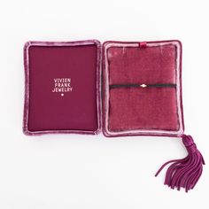 an open book with a tassel on the front and inside, sitting on a white surface