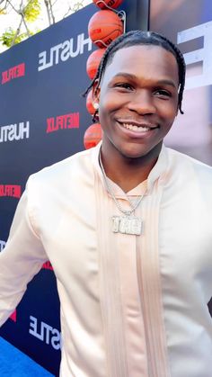 a man with dreadlocks standing in front of a blue carpet and red carpet