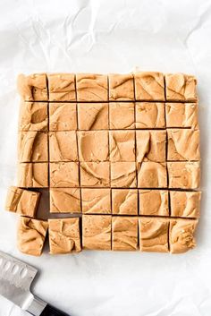 peanut butter fudge squares cut into squares on top of parchment paper with a knife