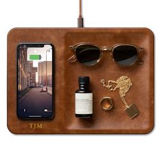 an iphone, sunglasses, and other items are arranged on a wooden tray