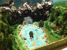 a model of a waterfall in the middle of a forest with trees and rocks around it