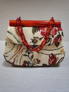 This vintage 1960's KADIN hand carry bag has a unique Lucite frame and Lucite links chain handle.  The floral tapestry has a neutral off white background with a beautiful floral pattern containing shades of reds/pinks, blues, greens, golds, browns, and a touch of lavender.  It is perfect for any occasion and season and is in mint/like new condition.  At the widest point it measures 12" and  9" at the narrowest across the top, and 3" deep.  It includes  protective feet, a turn lock closure and a long inside slit pocket and an inside zipper compartment. This is truly a statement bag to add to your handbag collection. Luxury Vintage Embroidered Bag, Hand Carry Bag, Ladies Bag, Handbag Collection, Statement Bag, Floral Tapestry, Carry Bag, Carry On Bag, Shades Of Red