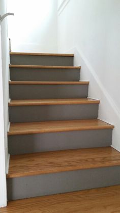 a set of stairs leading up to an upstairs room with wood floors and white walls