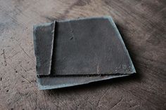 two square pieces of slate sitting on top of a wooden table next to each other