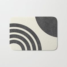 a bath mat with an abstract design in grey, yellow and white on the front