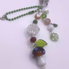 a close up of a necklace on a white surface with beads and charms hanging from it