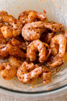 a glass bowl filled with fried shrimp on top of a wooden table