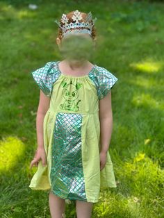 We make Kids dress-up clothes that are real garments you can wash and wear for years. The elastic neckline and sleeves, and flowing pattern means kids can wear the same dress from age 2 up to age 5+.   For this dress,  hand dyed cotton from new cotton sheets is the primary fabric with shinny dragon scale fabric for sleeves and front detail.  Adorable dragon on the front is a foil Cricut design. Dress comes  with a paper crown with  gold elastic head band. Green Short Sleeve Dress For Formal Occasions, Whimsical Princess Dress For Summer Fancy Dress, Whimsical Summer Princess Dress For Fancy Dress, Whimsical Summer Dresses For Play, Cute Green Dress For Dress-up Occasions, Cotton Short Sleeve Dress For Costume Party, Cute Green Dress For Dressy Occasions, Cute Green Dress For Costume Party, Green Fancy Dress For Summer