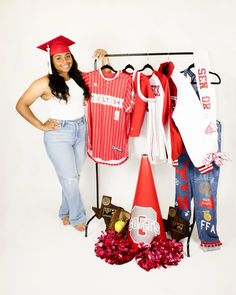 a woman standing next to a rack with baseball jerseys and hats on it's hangers