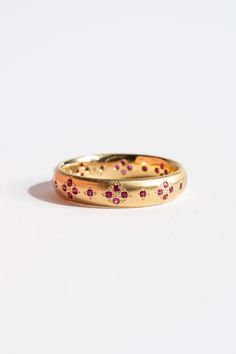 two gold wedding bands with pink flowers on the inside of each band, set against a white background