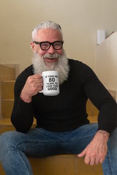 a man with a beard and glasses holding a pink coffee cup in his right hand