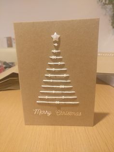 a card with a christmas tree on it sitting on a table next to a pile of books