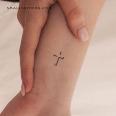 a woman's foot with a small cross tattoo on the left side of her arm