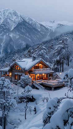 a house in the middle of a snowy mountain with lights on it's windows