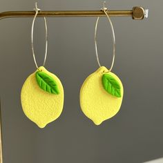 a pair of lemon shaped earrings with green leaves hanging from the back of it's ear wires