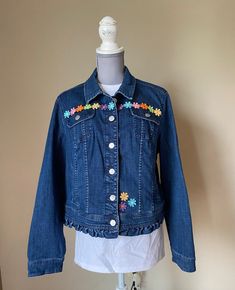 This upcycled denim jean jacket is a one-of-a-kind design with a bright flowers sewn on the front and back.  There is also a small ruffle on the bottom of the jacket.  A great spring jacket.  It is a womens size XL. Measures 18" across the shoulders, 22" from top of collar to bottom and sleeves are 24" long. Find more embellished jackets at our Etsy store, ClarettasCreations. Floral Print Denim Jacket For Summer, Spring Denim Jacket With Floral Print, Blue Denim Jacket With Floral Print, Spring Blue Denim Jacket With Floral Print, Bohemian Dark Wash Denim Jacket For Spring, Dark Wash Cotton Denim Jacket For Spring, Fitted Denim Jacket With Floral Print, Embellished Jackets, Embellished Jacket