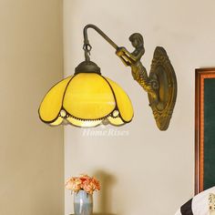 a lamp hanging from the side of a wall next to a table with a vase on it