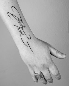 a black and white photo of a person's hand with a tattoo on it