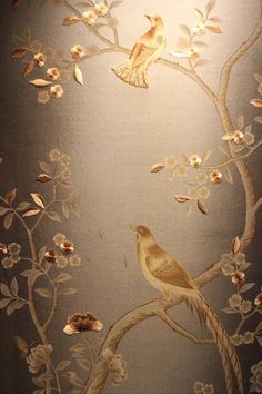 two birds sitting on a tree branch with flowers and leaves painted on the wall behind it