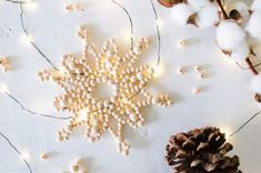 a snowflake is surrounded by cotton balls and pine cones on a white surface