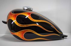 a black and orange motorcycle helmet with flames painted on the front, sitting on a white surface