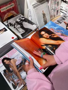 a woman is holding a magazine in her hand and looking at it on the table