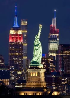 the statue of liberty is lit up in red, white and blue for the new york city skyline