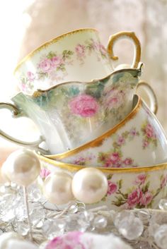 three tea cups and two saucers with pearls on the rims are sitting next to each other