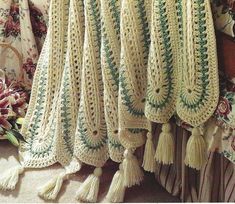 a crocheted blanket with tassels hanging from it's sides on a bed