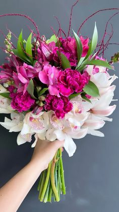 a bouquet of flowers is being held by a woman's hand on a gray background