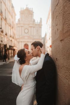 a bride and groom kissing on the street