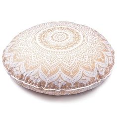 a white and gold round pillow on a white background with an intricate design in the middle