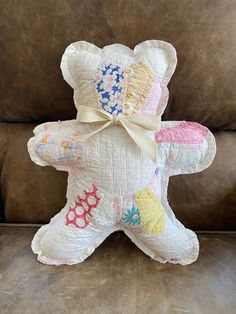 a white teddy bear sitting on top of a brown couch