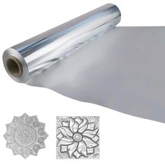 a roll of silver foil with an intricate design on the side and two medallions next to it