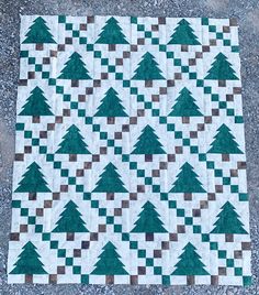 a green and white quilted christmas tree pattern on the ground, with brown squares