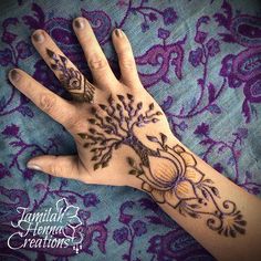 a woman's hand with henna tattoos on it and purple laces around the wrist